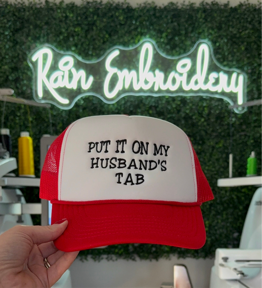 Put It On My Husband’s Tab Embroidered Trucker Hat